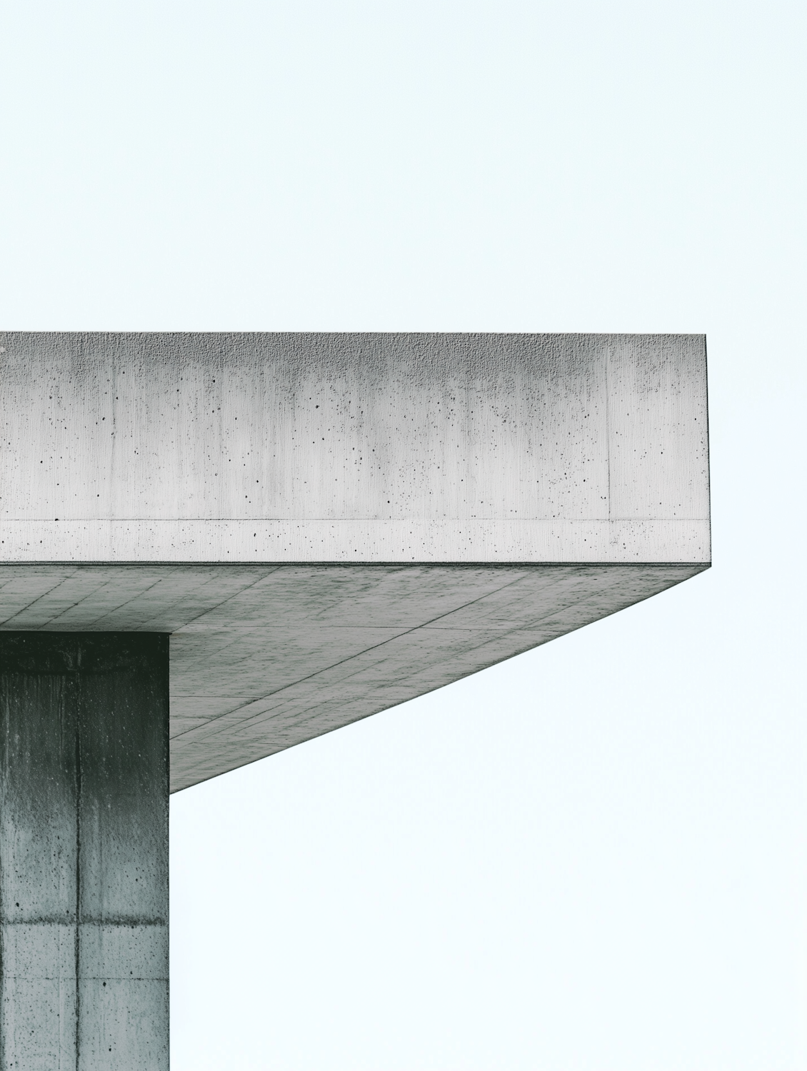Minimalist concrete facade against a pale sky